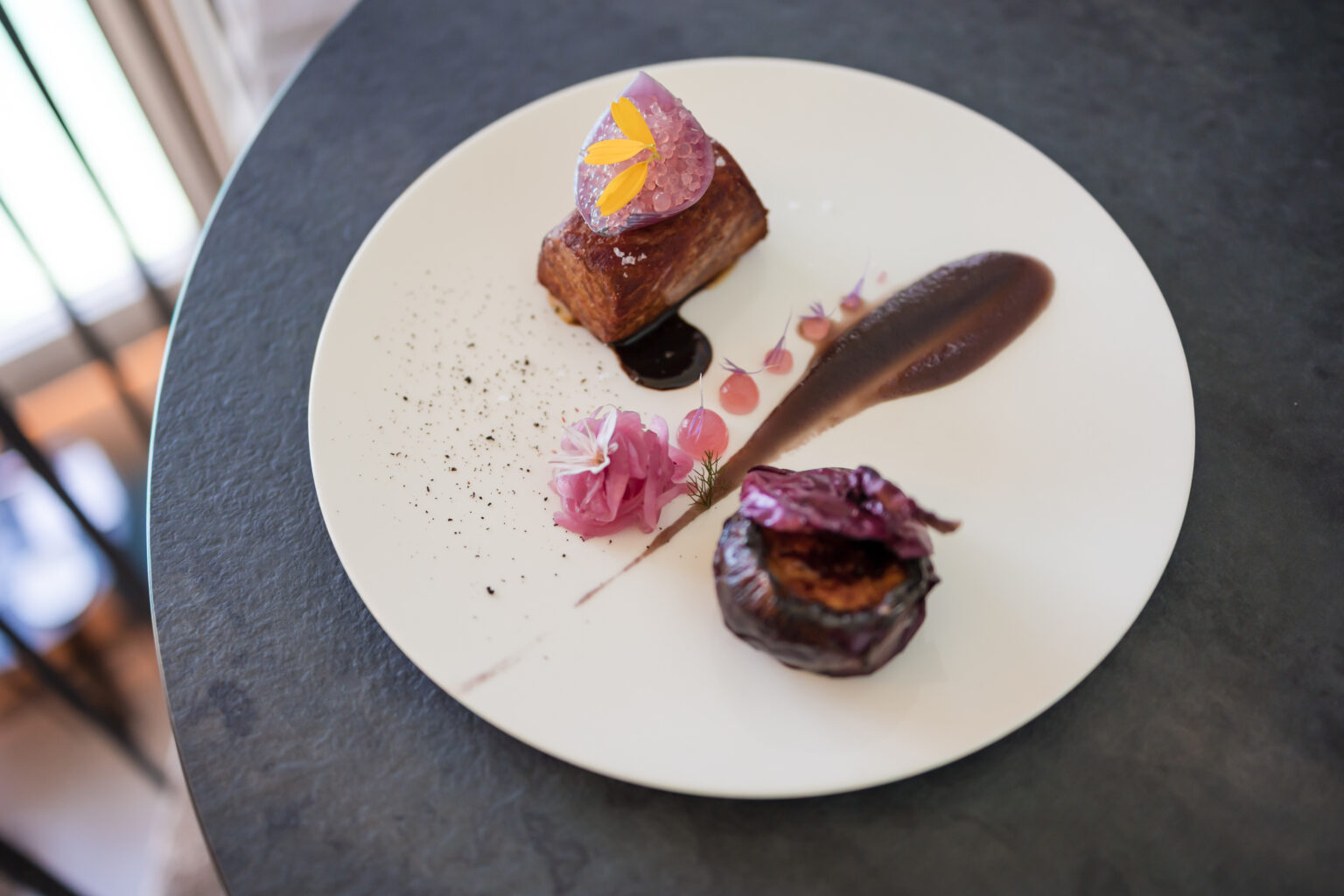 Piatto con tataki di Tonno e cipolla rossa di Tropea su un piatto bianco ed un tavolo scuro